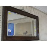 RECTANGULAR BEVEL EDGED MIRROR IN A STAINED OAK FRAME.