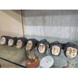 WALL MOUNTING POTTERY PIPE HOLDER MODELLED AS A ROW OF SEVEN COWLED HEADS