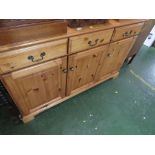 HONEY PINE SIDEBOARD WITH THREE DRAWERS OVER THREE CUPBOARD DOORS.