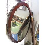 OVAL WALL MIRROR IN A SHAPED MAHOGANY FRAME.