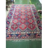 LARGE RED GROUND PATTERNED FLOOR RUG WITH THREE MARGINS AND TASSELLED ENDS.