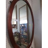 OVAL BEVEL EDGED MIRROR IN A BANDED BOXWOOD STRUNG MAHOGANY FRAME.