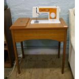 A Singer 6101 sewing machine: on flip top wooden storage table/stand.