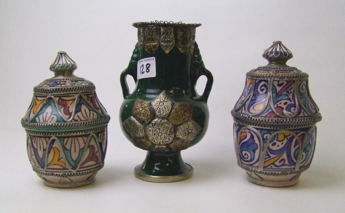 A pair of pottery lidded pots: with hand painted and metal decoration together with a similar twin