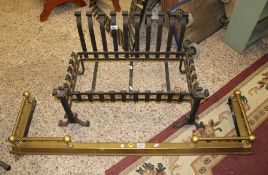 A large wrought iron dog grate: together with a vintage brass hearth fender: grate 87cm in width.