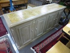 A South African painted hardwood four door cupboard having tiled top