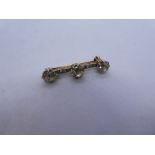 Antique unmarked two tone bar brooch with central circular cut diamond flanked with two oval cut dia