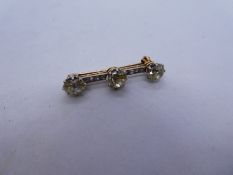 Antique unmarked two tone bar brooch with central circular cut diamond flanked with two oval cut dia