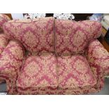 Victorian style modern two seat sofa upholstered in red fabric with gold floral decoration on castor