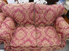 Victorian style modern two seat sofa upholstered in red fabric with gold floral decoration on castor