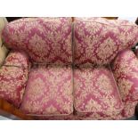Victorian style modern two seat sofa upholstered in red fabric with gold floral decoration on castor