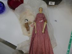 An antique wooden articulated doll in original clothing and a small Bisque headed example