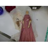 An antique wooden articulated doll in original clothing and a small Bisque headed example