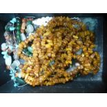 A box of costume jewellery including jade necklace, and two strings of amber coloured beads