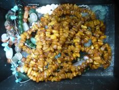 A box of costume jewellery including jade necklace, and two strings of amber coloured beads