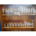 Three shelves of good quality crystal drinking glasses, including a set of six Laura Ashley red glas