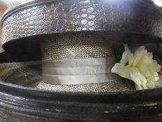 A decorative crocodile skin style box containing hats and ties