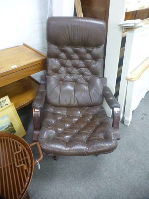 A 1970's style brown leather buttonback armchair on swivel base