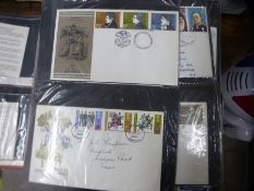 A red folder containing a number of First Day Covers