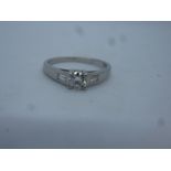 Platinum solitaire diamond ring with central 0.25 carat brilliant cut diamond flanked tapered baguet