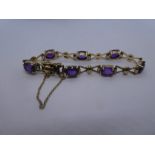 9ct yellow gold bracelet with bow design links and 7 oval facet cut amethyst, marked 375 with safety