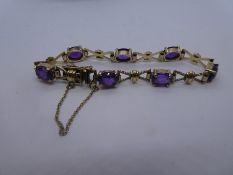 9ct yellow gold bracelet with bow design links and 7 oval facet cut amethyst, marked 375 with safety