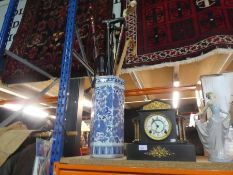 A slate mantle clock with gilded decoration and a blue and white stick stand with walking sticks