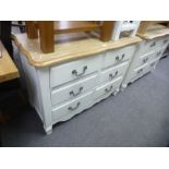 A pair of modern cream six drawer chests having oak tops