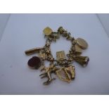9ct yellow gold charm bracelet hung with 14 charms including passport, poodle, whisky bottle, harp,