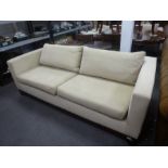 A pair of modern beige sofas having mahogany bases, each 198 cms