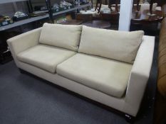 A pair of modern beige sofas having mahogany bases, each 198 cms