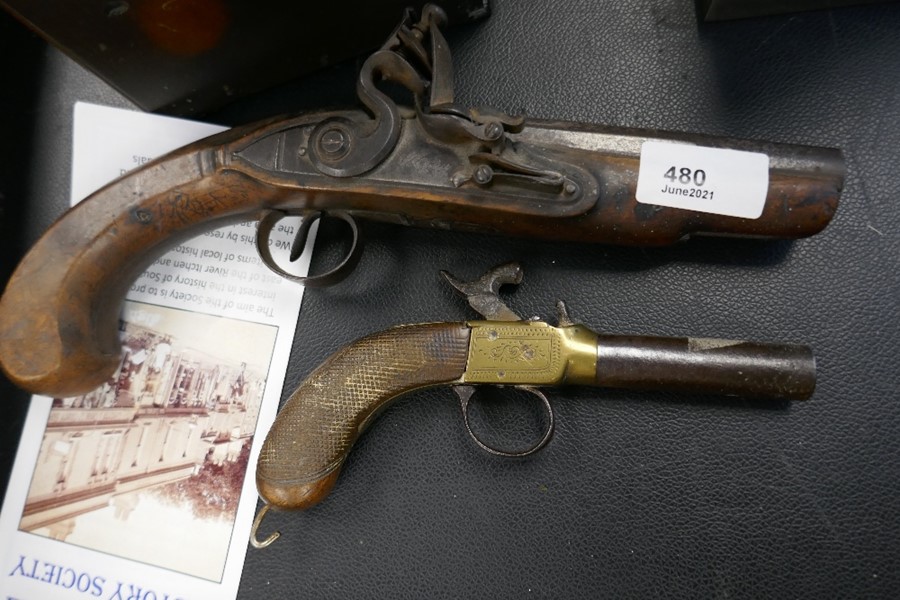 An old flintlock pistol and a small percussion pistol