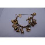 9ct yellow gold charm bracelet hung with approx 15 9ct yellow gold charms, and one white metal examp