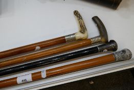 Three Malacca canes and an ebonised example with silver knobs or collars