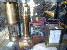 An old brass miners lamp, a carriage clock and a brass lighthouse lamp