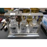 A silver plated tantalus having three glass decanters, two with silver wine labels