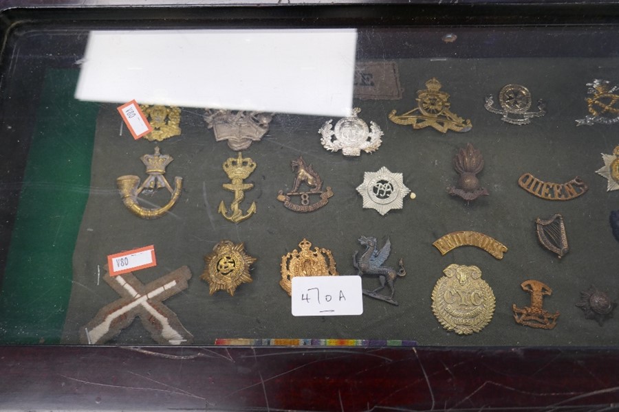 A small glazed display case containing military badges and similar.