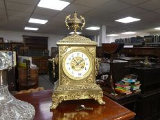 An early 20th century ornate brass chiming mantel clock with urn surmount and scroll feet