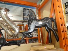 A black wooden statue of a fairground horse