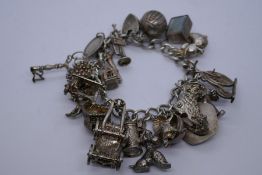 Vintage silver charm bracelet hung with approx 20 charms incl. hedgehog, key, ice skate etc 102.5g