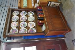 A reproduction mahogany bookcase having two drawers with cupboard below and twelve Franklin Mint flo