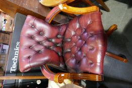 Two similar red leather revolving desk chairs, with buttoned seats and backs