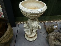 A small ornate bird bath decorated with cherubs