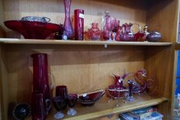 Two shelves of Cranberry glass and similar