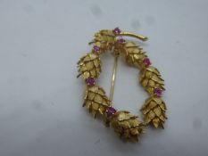 Unmarked yellow metal oval brooch in the form of pine cone wreath separated with rubies, approx 5cm,