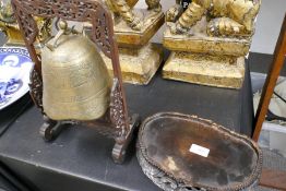 A Chinese engraved brass bell on wooden pierced stand and a Chinese carved hardwood stand