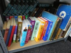 A full shelf of books including a vintage suitcase