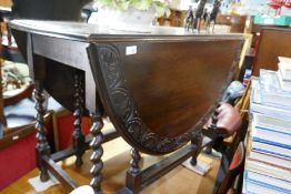 A carved oak two flap gateleg table on barley twist legs