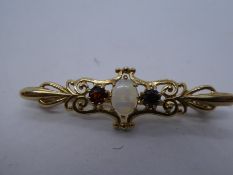 9ct yellow gold bar brooch set with central cabochon white opal flanked two circular garnets, marke