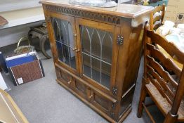 A reproduction oak leaded glass bookcase with cupboard below, 101cm